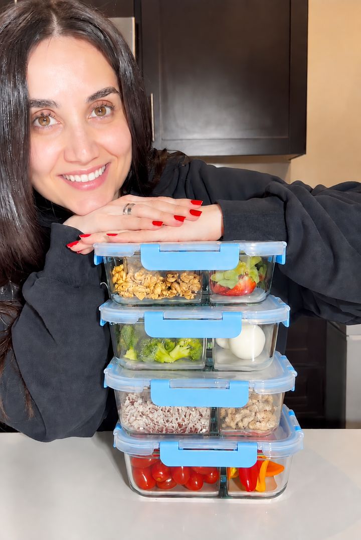 Customer smiling behind a stack of four prepped glass meal prep containers