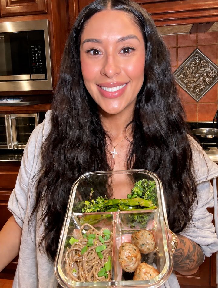Customer holding a glass container with soba noodles, broccolini and meatballs